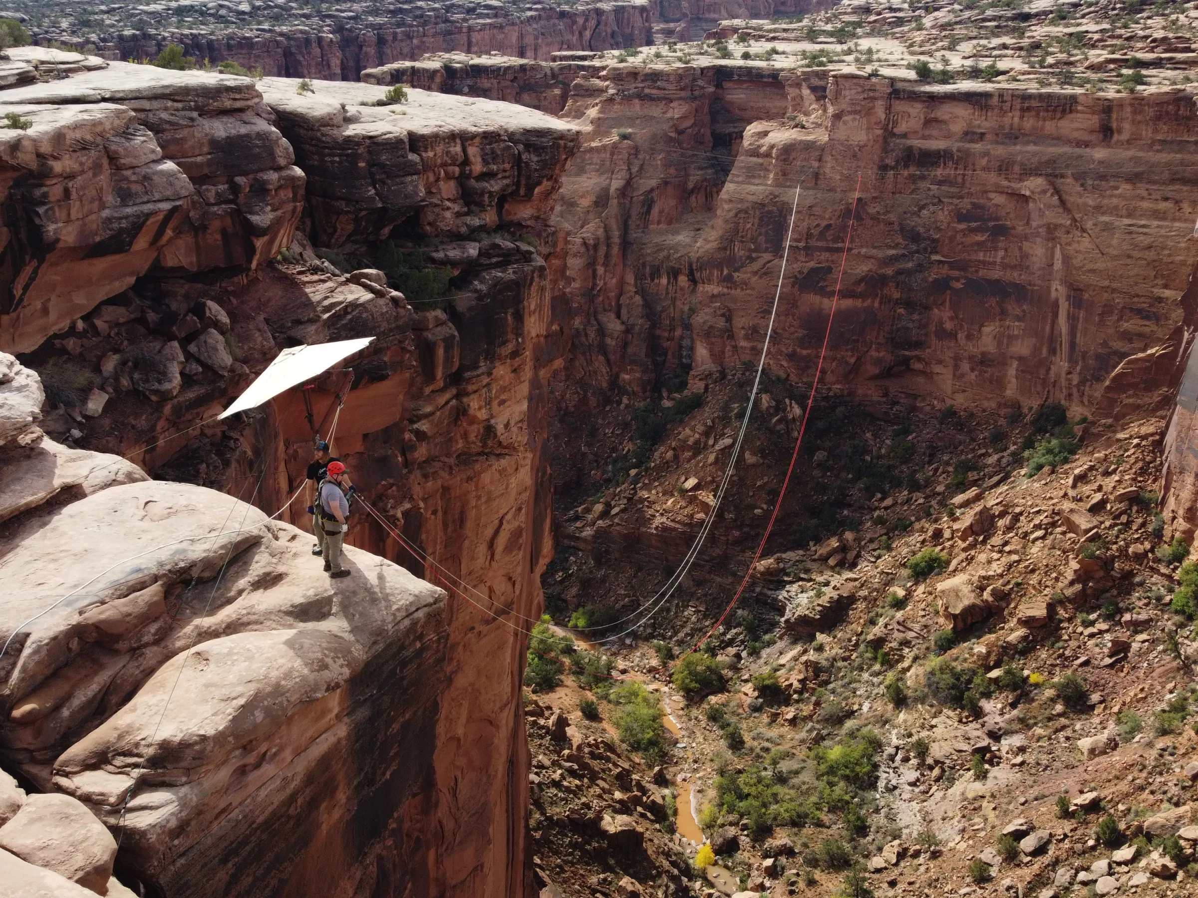 Person with a hang glider preparing to jump off a rocky cliff in a canyon landscape.