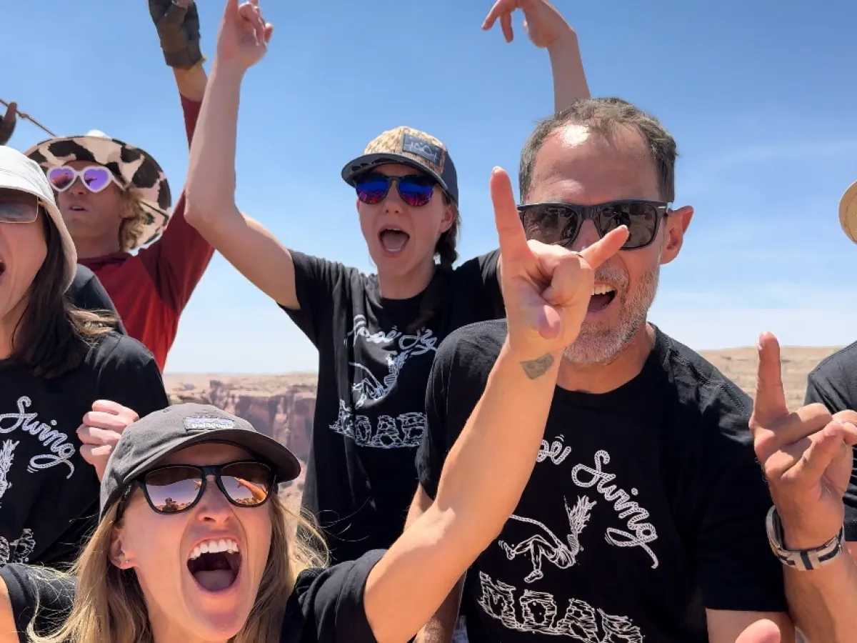 Group of excited people outdoors wearing sunglasses and matching 'Rope Swing' shirts.