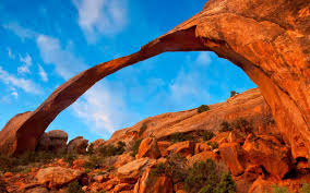 Delicate Arch in desert landscape against a bright blue sky.