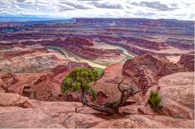 Scenic view of a canyon with a winding river and rocky cliffs under a cloudy sky.
